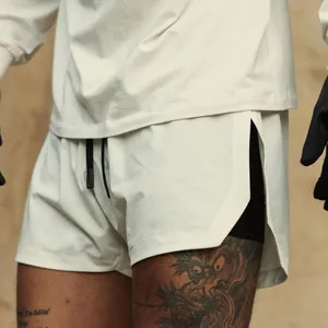 Macro view of cream men's double-layer athletic shorts showing side slit and inner mesh lining.