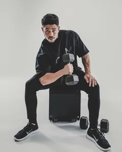 Model wearing black oversized fitness t-shirt while holding a heavy dumbbell gym shot.