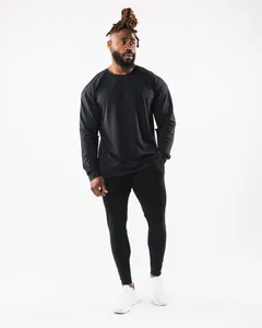 Model trägt ein schwarzes Langarm-Sport-T-Shirt und schmale Jogginghosen im Studio.