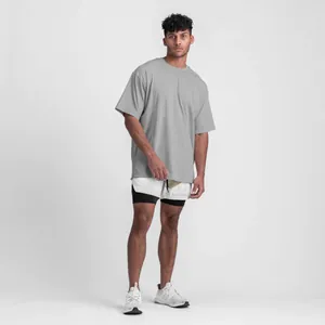 Full body shot of a male model wearing an oversized grey cotton T-shirt with athletic shorts