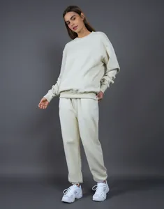 Vista de cuerpo completo de una modelo con sudadera extragrande beige y conjunto de jogging.