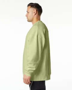Side profile view of a man wearing a sage green oversized fleece crewneck sweatshirt.