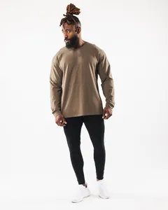 Vollansicht eines Mannes in einem braunen langärmeligen Oversize-Sport-T-Shirt vor Weiß