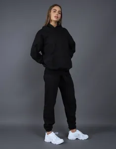 Female model wearing a heavy black oversized hoodie and matching sweatpants set in a studio