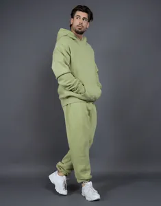 Full body view of a male model wearing a loose avocado green fleece tracksuit set
