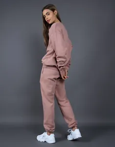 Mujer con un conjunto de chándal de forro polar color malva sobre un fondo gris neutro