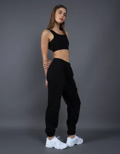 Modella che indossa pantaloni della tuta in pile nero pesante, scatto in studio