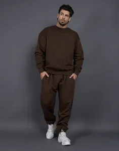 Vista completa de un hombre con un chándal de forro polar marrón oversize y zapatillas
