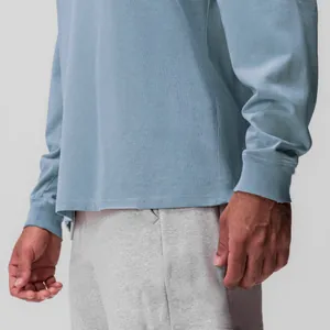 Primo piano di t-shirt da uomo azzurra a maniche lunghe con texture del tessuto e polsini.