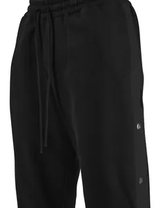 Dettaglio ravvicinato dei pantaloni da basket in pile nero con bottoni laterali.
