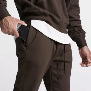 Detailansicht eines Smartphones in der Tasche einer braunen Herren-Jogginghose.