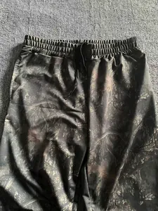 Close-up of men's loose jogging pants featuring a dark forest digital camo pattern