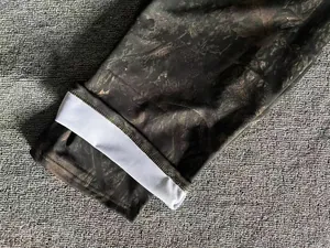 Detailed close-up view of men's forest camouflage jogger pants with elastic cuff