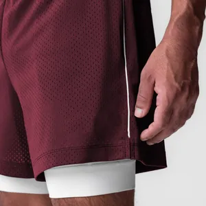 Detalle de pantalones cortos de malla granate con capa de compresión blanca