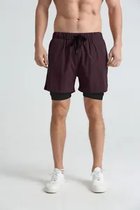 Full view of men's double-layer sports shorts with black liner on a model in studio