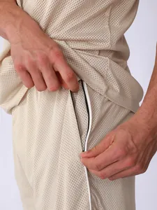 Detailed macro view of beige mesh fabric and pocket design on men's breathable sports shorts
