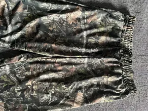 Close-up detail of men's jogger pants with realistic forest leaf camouflage pattern