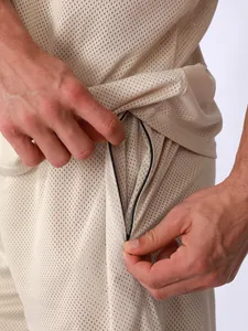 Détail du tissu en maille respirante et de la poche zippée d'un short de sport beige