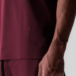 Gros plan du tissu en maille bordeaux respirant sur ce débardeur de sport pour homme