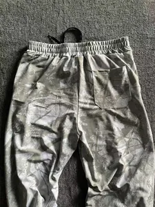 Detailed view of men's loose camouflage sports joggers with digital forest pattern and back pocket