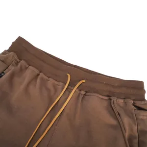 Detail of brown cotton sports shorts featuring an elastic waistband and yellow drawstring.