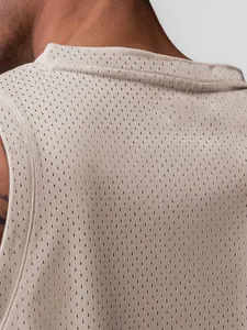 Gros plan sur le tissu en mesh beige respirant d'un débardeur de basket pour hommes
