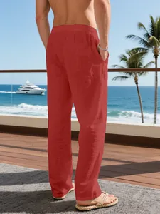Back view of red loose linen trousers for men in a tropical holiday resort setting.