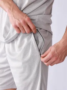 Détail du short de sport en maille grise respirante avec poche zippée sécurisée.