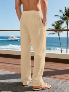 Back view of men's loose beige linen trousers in a tropical seaside resort setting