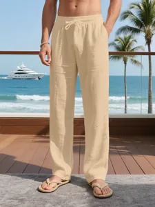 Men's loose breathable linen vacation pants with drawstring waist in a beige beach setting