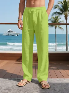 Detail of lime green men's linen pants with drawstring waist in a beach setting.
