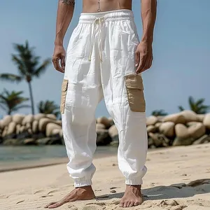 Close-up of men's white linen joggers featuring khaki cargo pockets in a beach setting