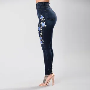 Women's high-waisted dark blue skinny jeans with light blue floral embroidery detail.