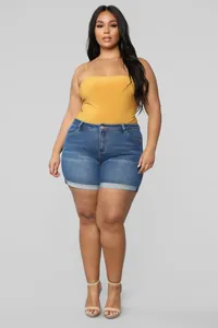 Close-up of plus size stretchy denim shorts in classic blue wash worn by a model
