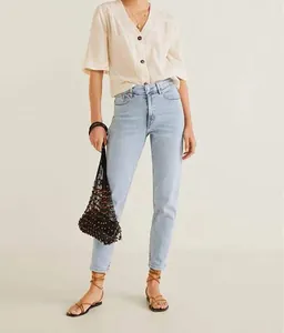 Model wearing light blue high waist slim straight jeans with beige shirt and bag