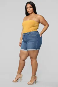 Side view detail of blue plus-size stretch denim shorts with a cuffed hem on a model.