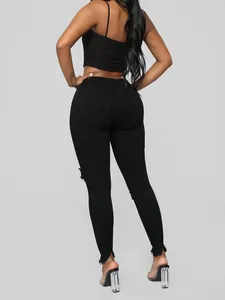 Vista posterior de vaqueros skinny negros de talle alto con rotos y dobladillo