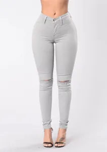 Dettaglio di jeans skinny elasticizzati grigi a vita alta con strappi sulle ginocchia