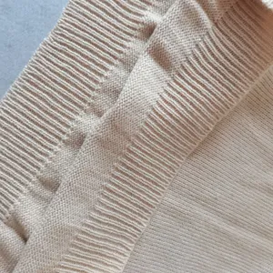 Dettaglio macro della trama in maglia a coste beige sulla manica di un maglione