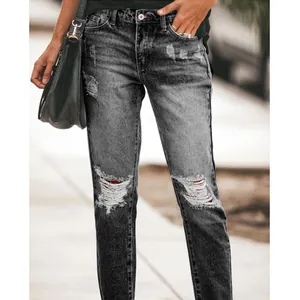 Detail shot of women's grey ripped straight-leg jeans in a street style setting