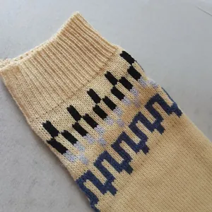 Dettaglio macro della manica di un maglione lavorato a maglia con motivi in beige