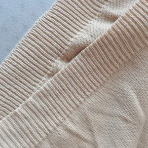 Dettaglio della trama del maglione beige a costine con cuciture di alta qualità