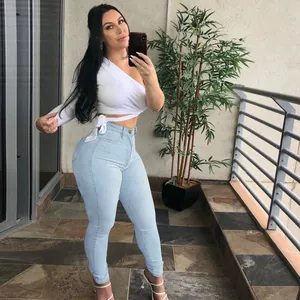 Mujer con vaqueros ajustados elásticos de talle alto azul claro en selfie en el balcón