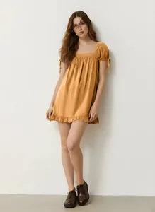 Detail view of mustard yellow square neck mini dress with ruffled hem and sleeve ties.