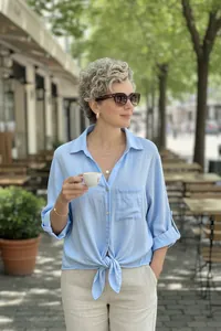 Casual light blue tie-front button-down shirt worn in outdoor cafe setting