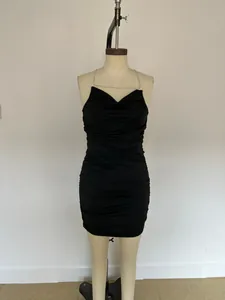 Gros plan d'une mini-robe moulante froncée noire avec d'élégantes bretelles en chaîne argentée