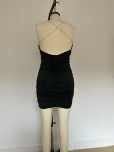 Vue arrière détaillée d'une robe noire plissée avec des détails de chaîne croisée au dos.