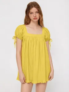 Detail of yellow square neck top featuring puff sleeves with ribbon tie accents