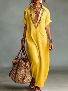 Detailed close-up view of a yellow loose linen dress featuring embroidery and front pocket