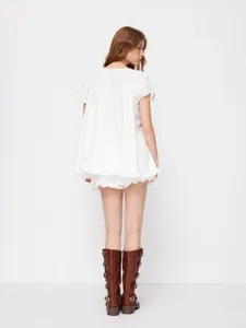 Rear view of white ruffled shirt and lace-edge shorts paired with brown boots.